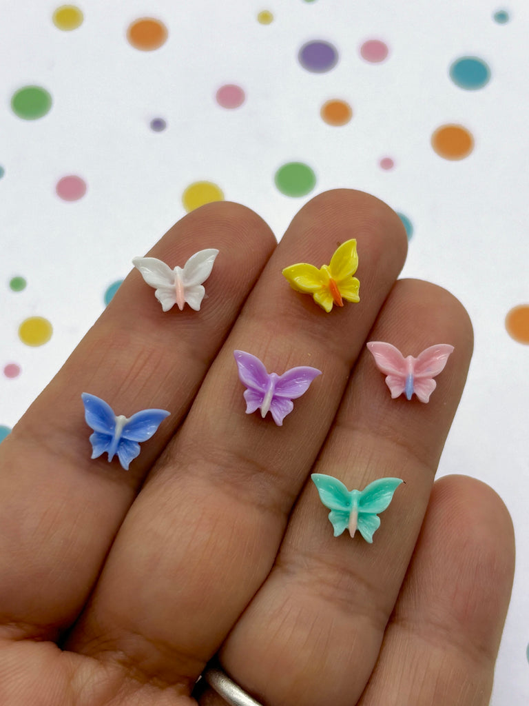 a person's hand holding four small butterflies