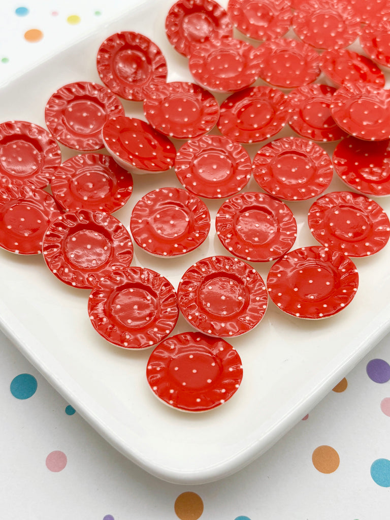 a white plate with a collection of red, round, polka-dotted objects arranged on it.