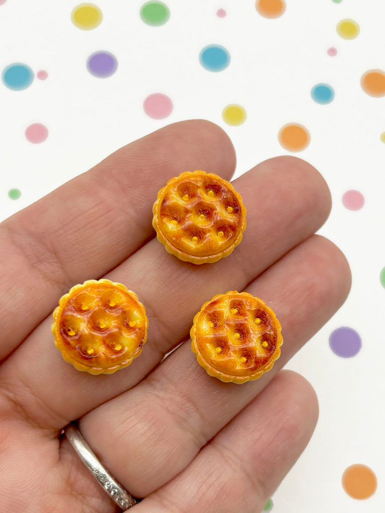 A hand holding three small, round pastries against a background with colorful polka dots.