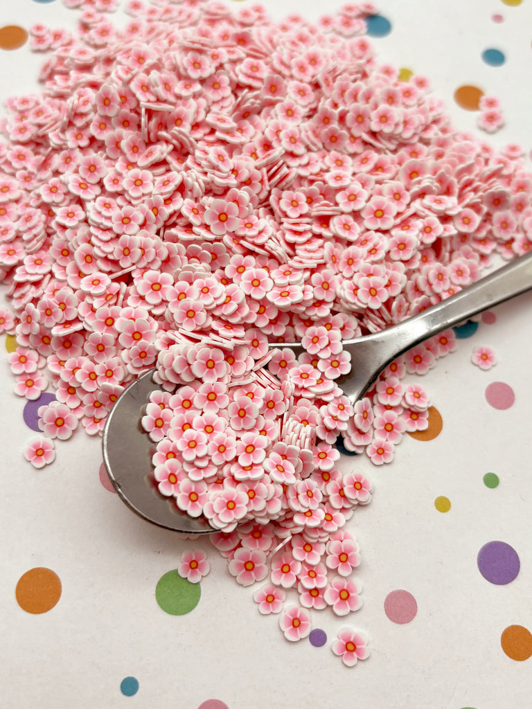 a spoon filled with pink flowers sitting on top of a table