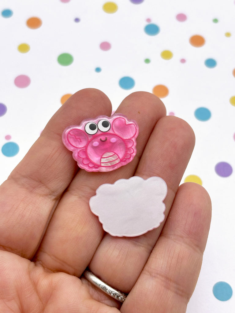 a hand holding a small pink object with eyes