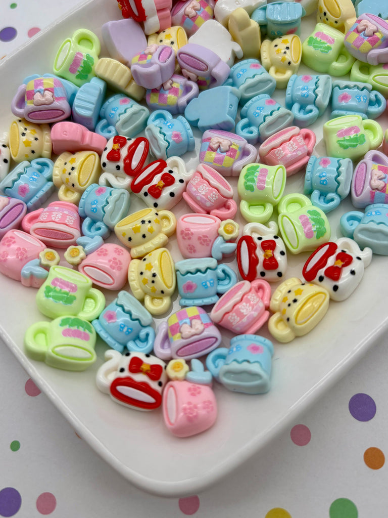 a white plate filled with a variety of colorful, cartoon-like tea cups and saucers.