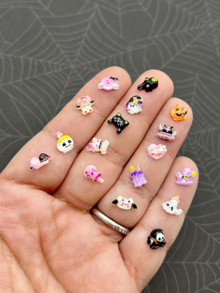 A hand holding a collection of small, colorful nail art stickers on the fingers.