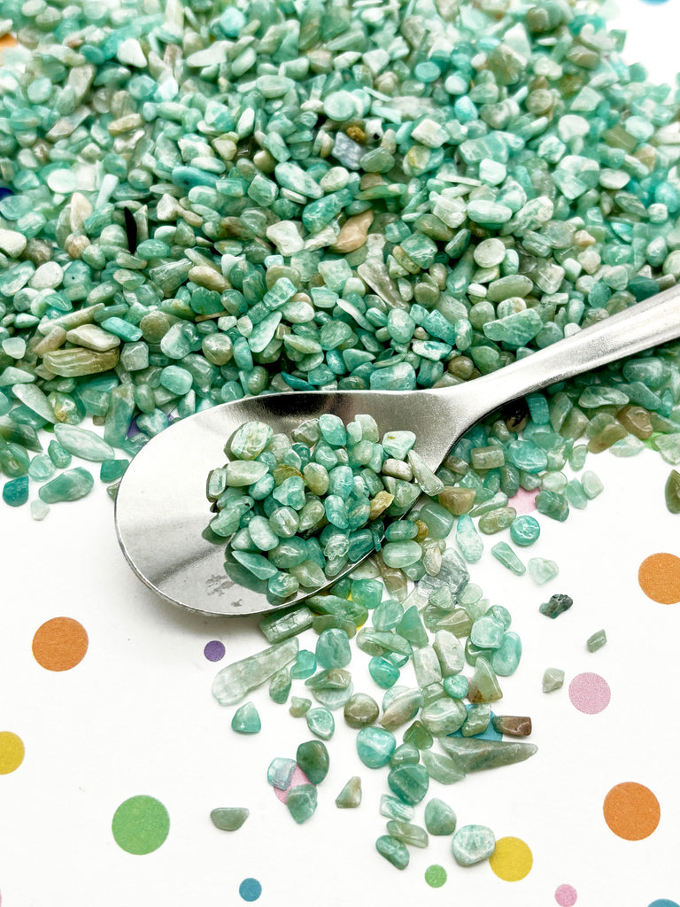 a spoon filled with green sprinkles on top of a table