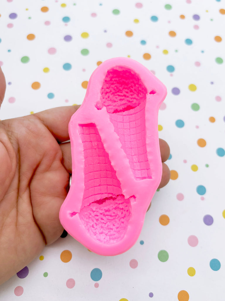 A hand is holding a pink, textured object that appears to be a mold or a similar shape. The background is a colorful polka dot pattern.