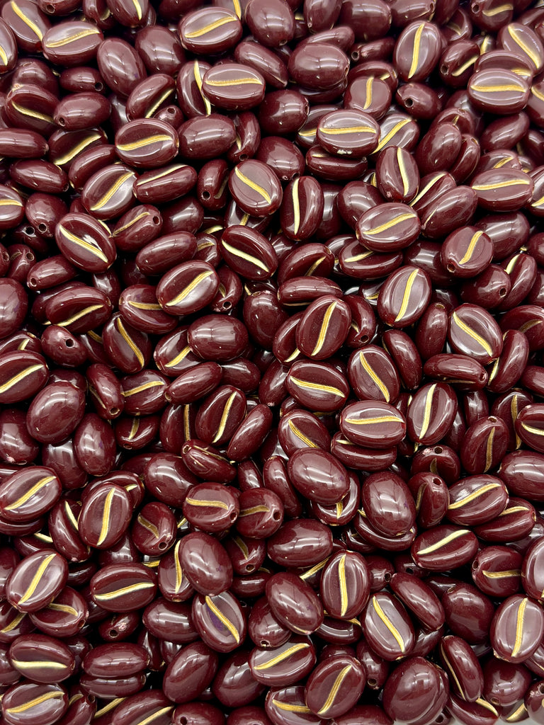 a close-up view of a large pile of dark brown, oval-shaped beads with a yellow stripe running through them.