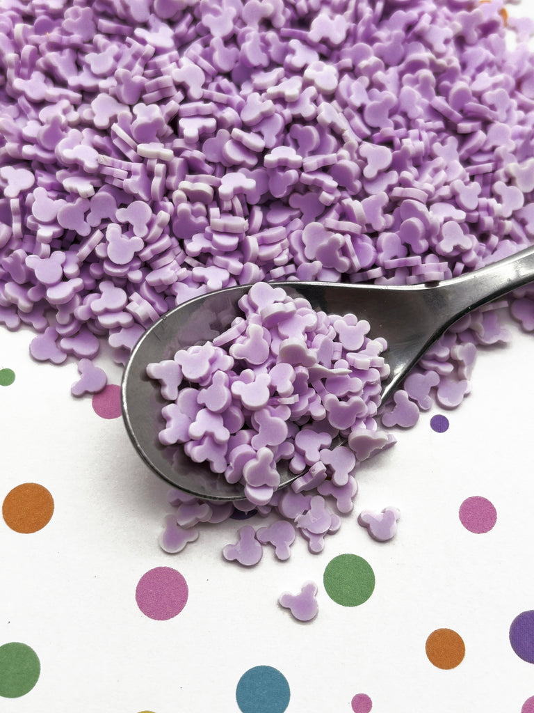 a spoon full of purple sprinkles on a polka dot tablecloth