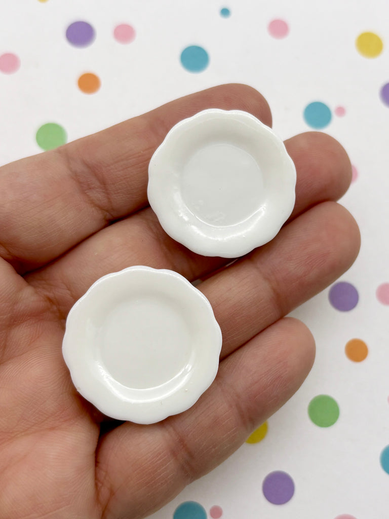 A hand holding two small white plates against a background with colorful polka dots.