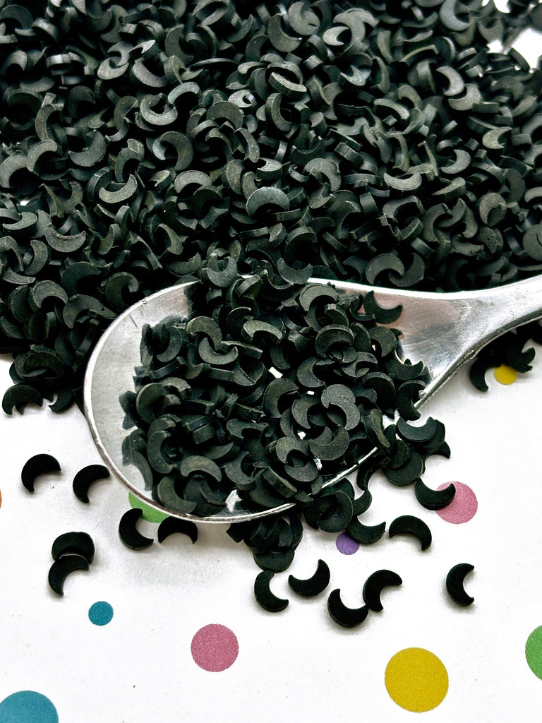 a spoon full of black sprinkles on a polka dot tablecloth