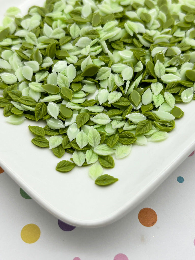 a white plate topped with green leaves on top of a table