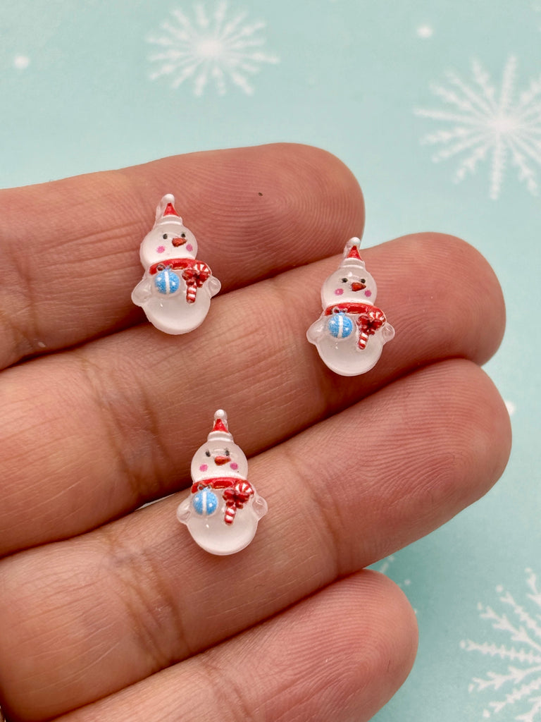 a hand holding a pair of tiny christmas ornaments