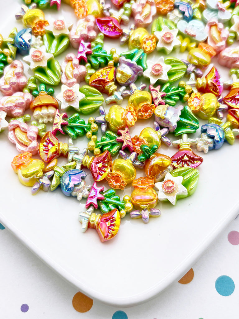 a variety of colorful beads and charms, including flowers, leaves, and stars, arranged on a white plate.
