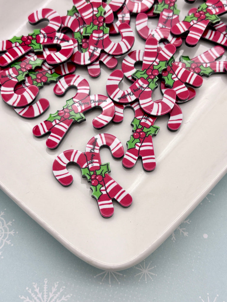 a white plate with a collection of red and white candy canes arranged on it.