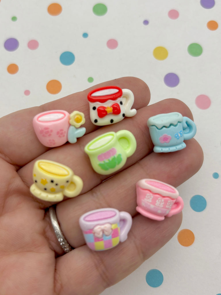 A hand holding a collection of colorful, whimsical tea cups against a background with polka dots.