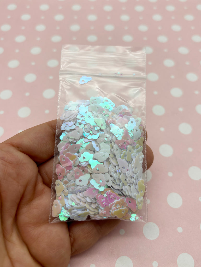 a hand holding a bag of sequins on a pink background