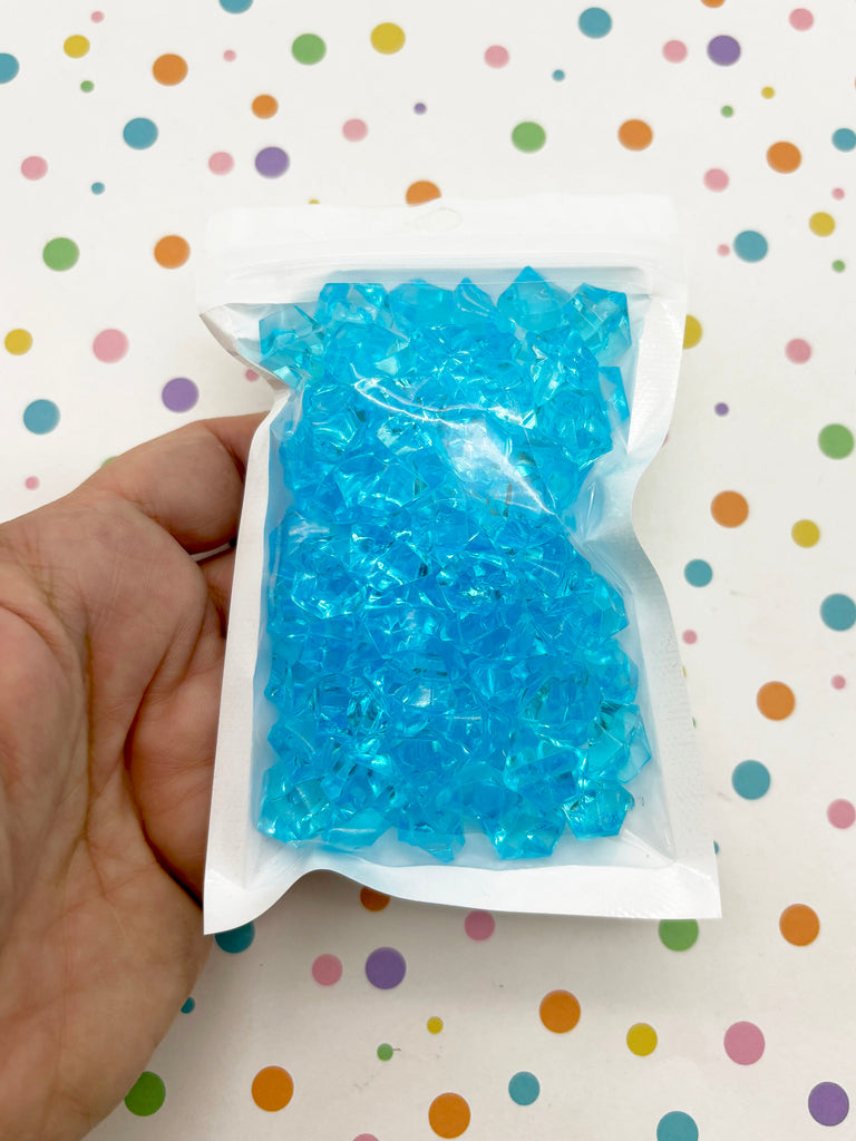 a hand holding a bag of blue beads