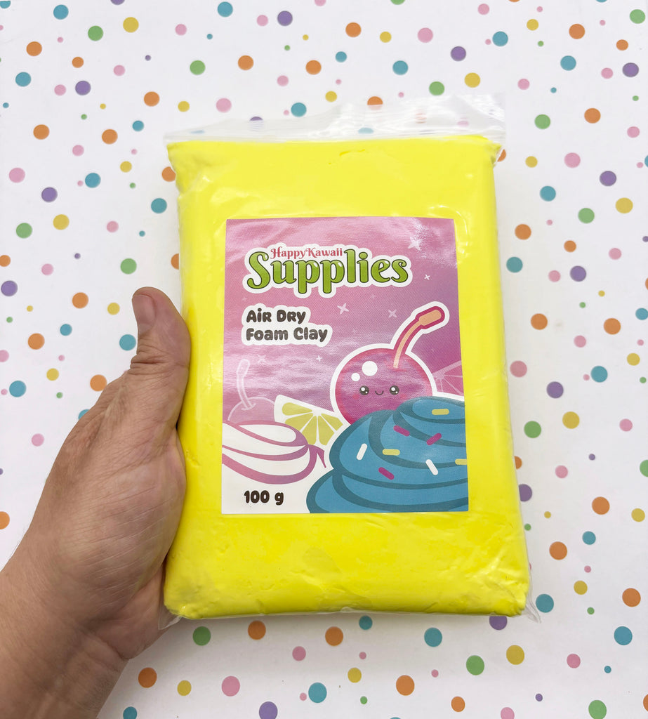 A hand is holding a yellow bag of Happy Kowai Supplies' Air Day Foam Clay, which is a 100g bag.