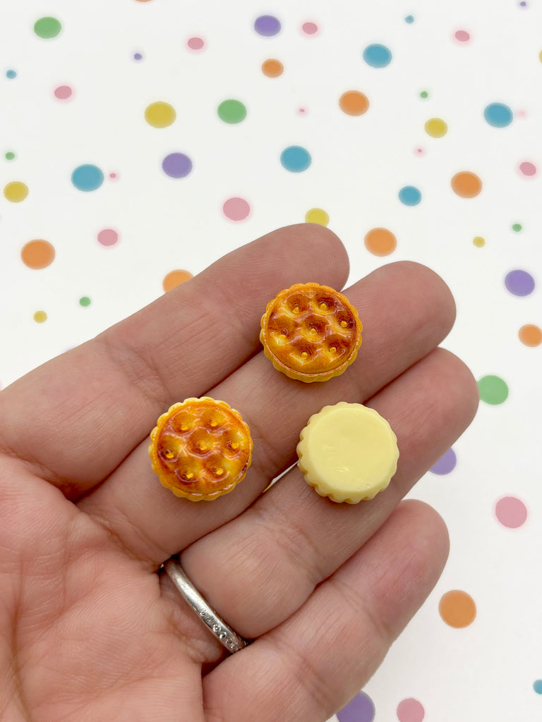 A hand holding three small, round pastries against a background with colorful polka dots.