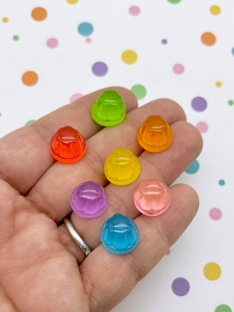 A hand holding seven colorful jellybean-shaped objects against a background with polka dots.