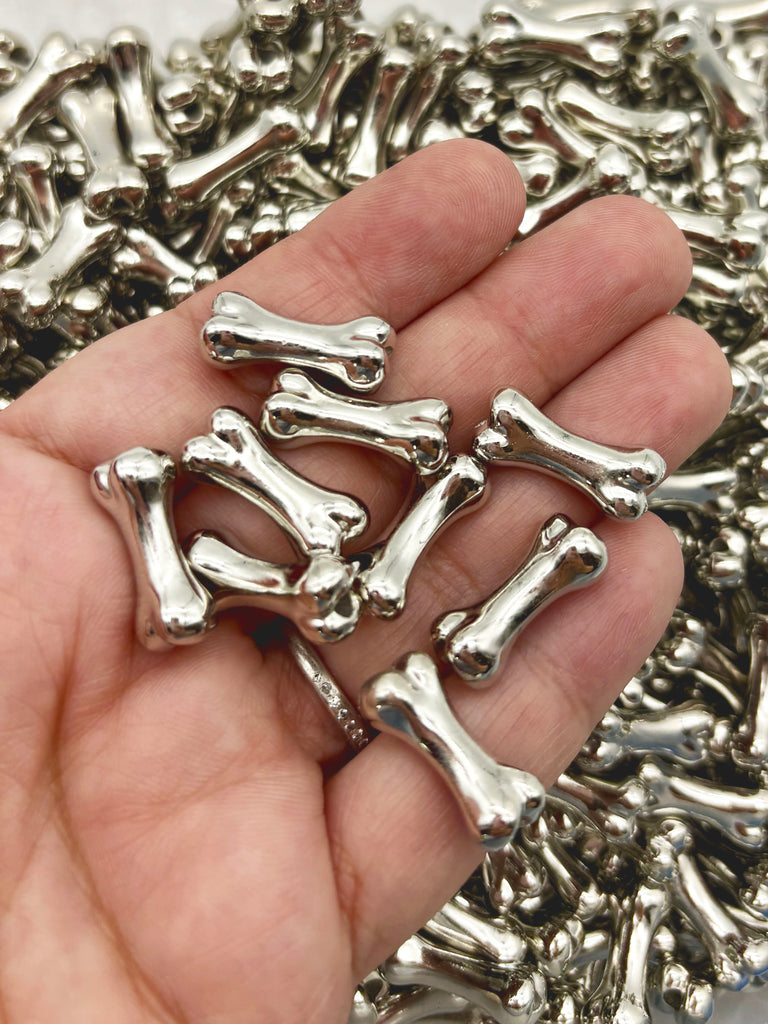 A hand holding a pile of small, shiny metal bones.