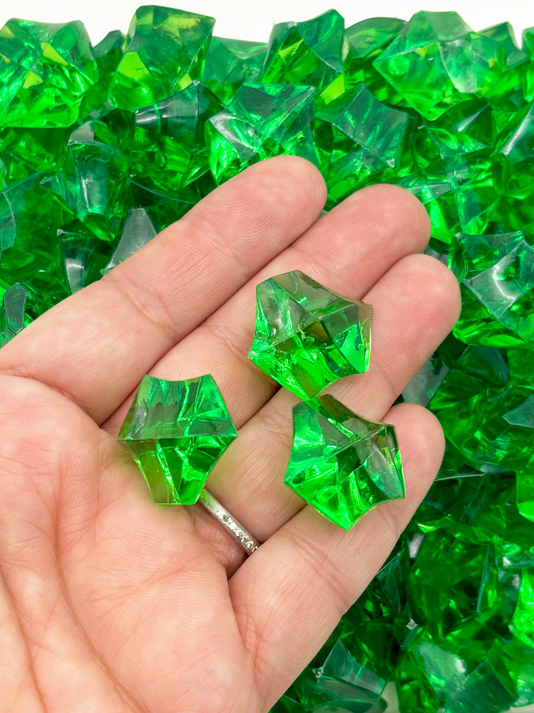a hand is holding three green cubes of glass