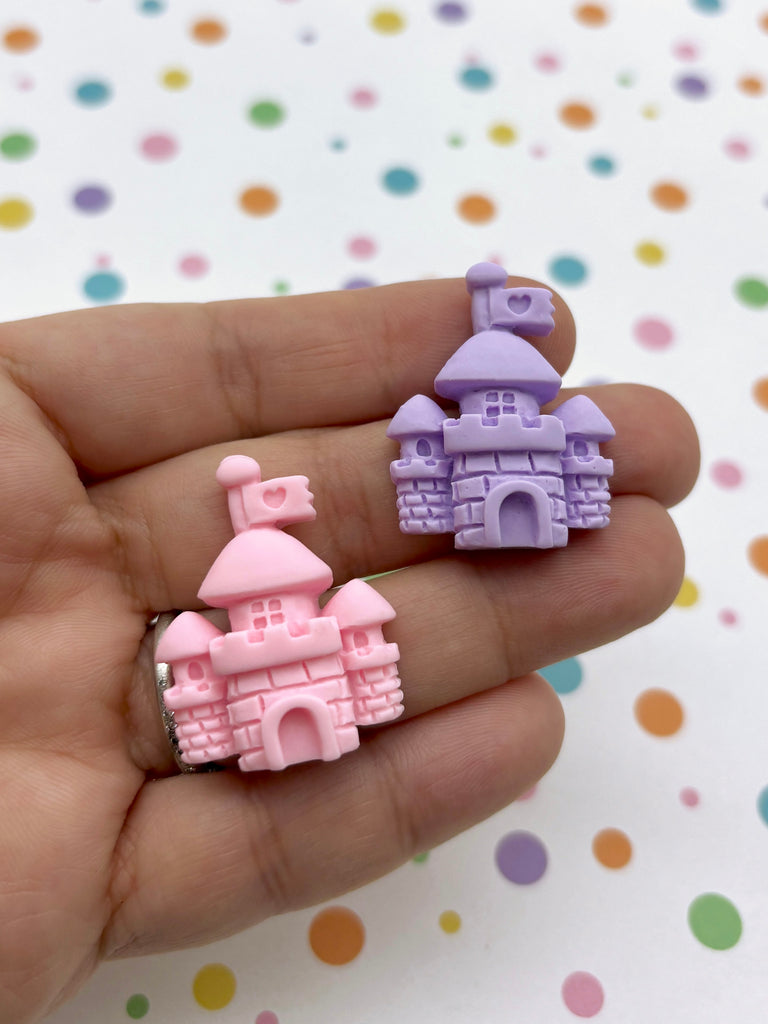 a hand holding a small pink and purple castle