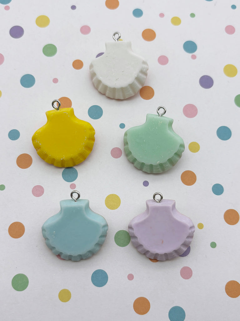five colorful seashell-shaped charms, each with a unique color and design, arranged on a background with polka dots.