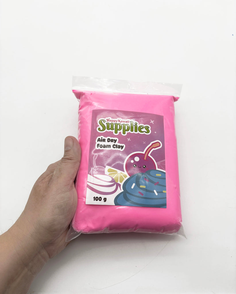 A hand holding a package of pink air day foam clay.