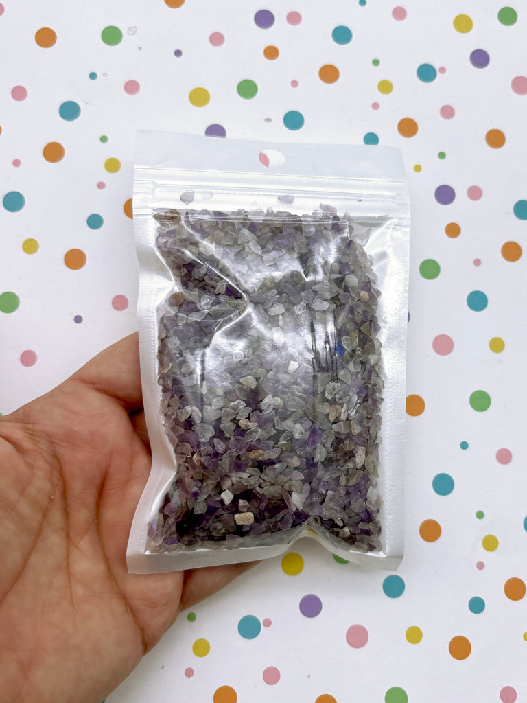 a hand holding a bag of purple and silver glitter