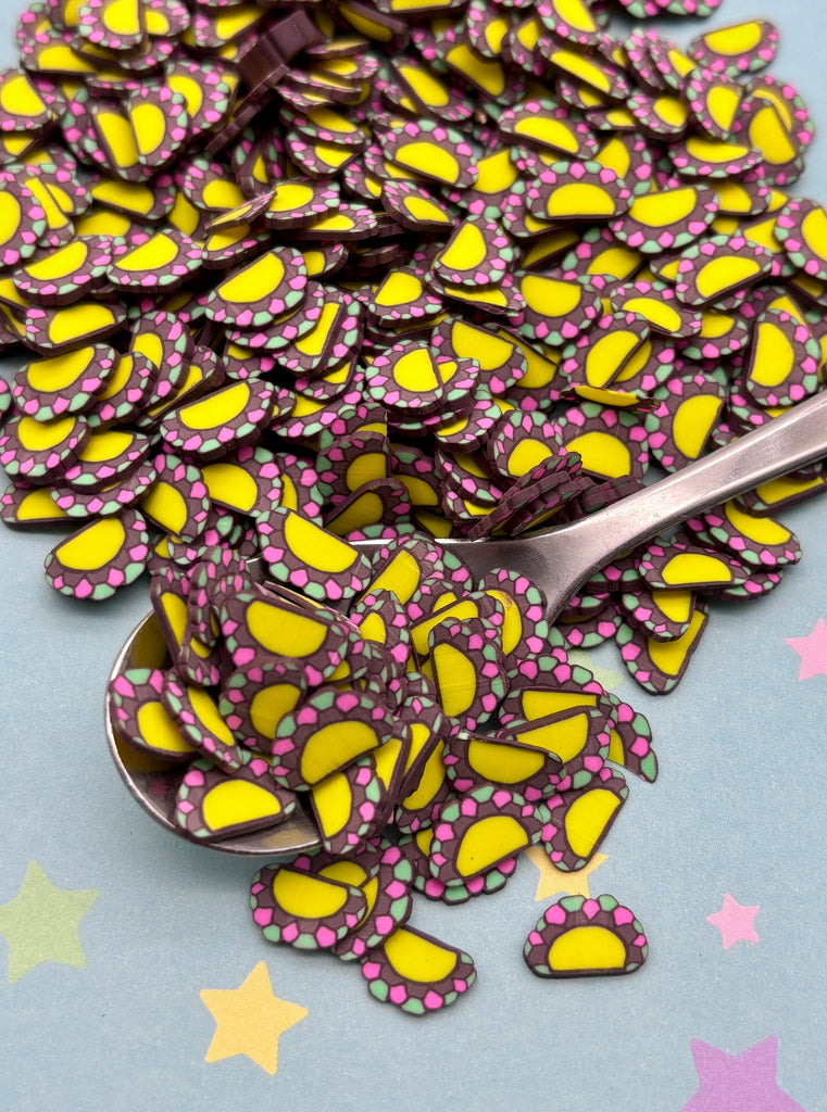 a pile of yellow and pink paper butterflies next to a spoon