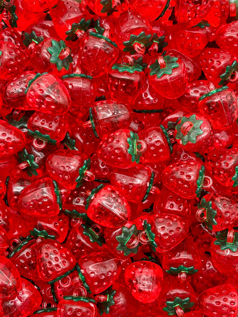 The image is a close-up of numerous red plastic strawberries with green stems, arranged in a visually appealing manner.