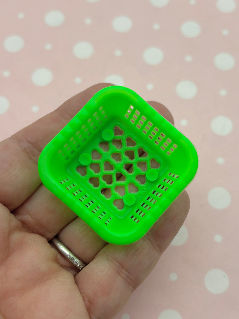 A hand holding a small green plastic basket with a grid pattern.