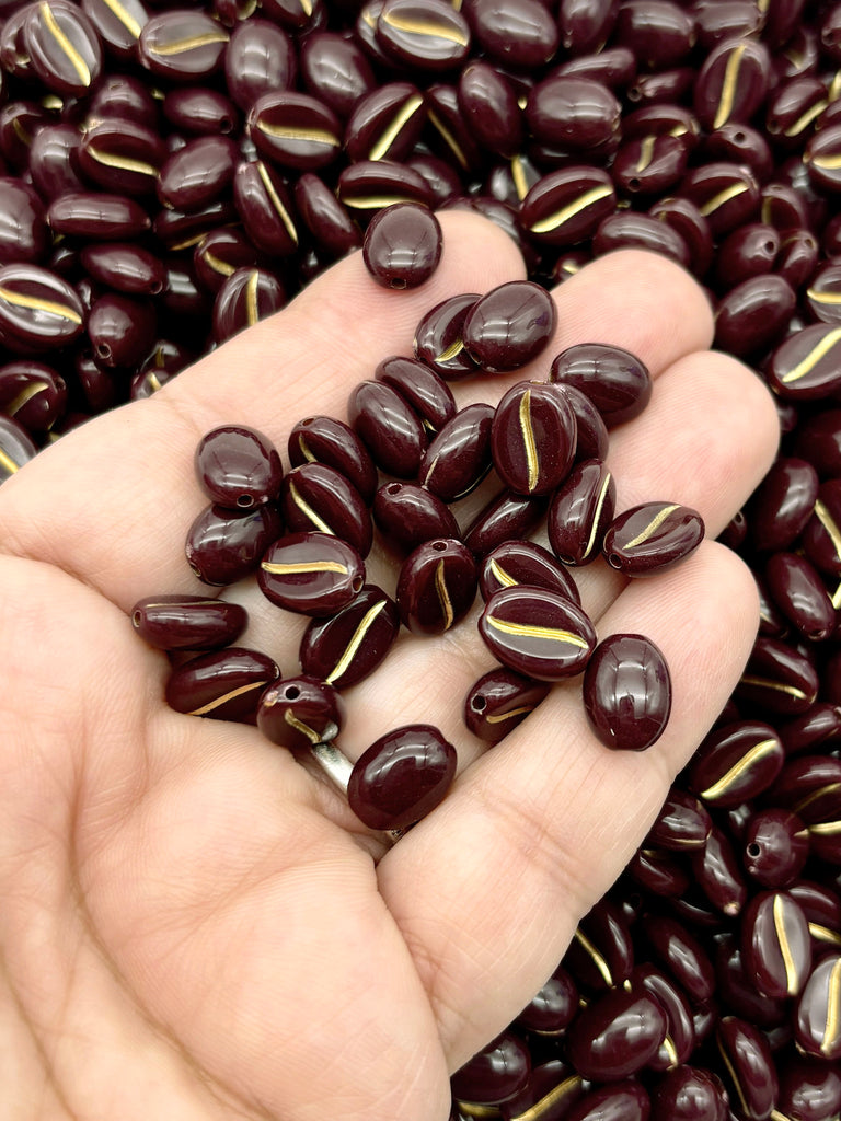 A hand holding a pile of dark brown beads with gold accents, which appear to be beads or beads with a similar color scheme.