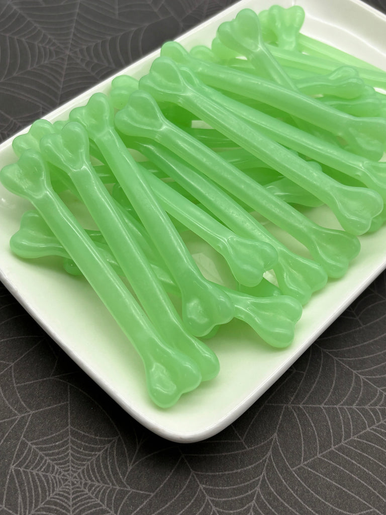 A white rectangular plate holds a collection of green, glowing plastic bones arranged in a pattern.