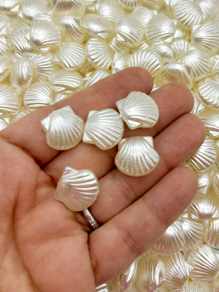 a hand is holding five seashells on a table