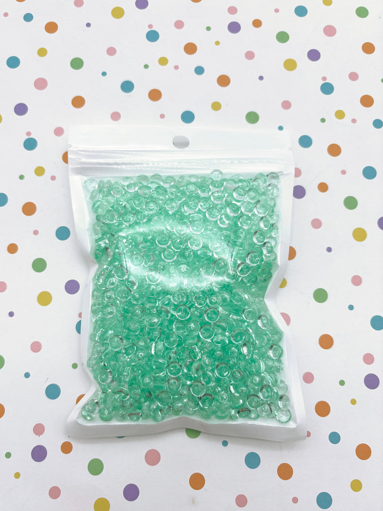 a bag of green beads sitting on top of a table