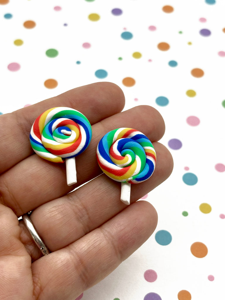 a person holding two lollipops in their hand