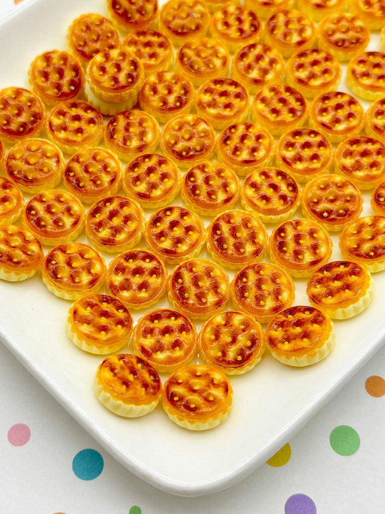 a white plate filled with small, round, golden-brown cookies arranged in a pattern.