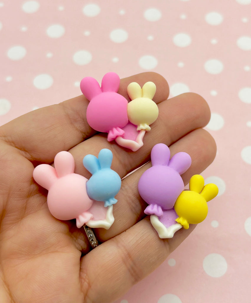 a person is holding three small toy bunnies in their hand