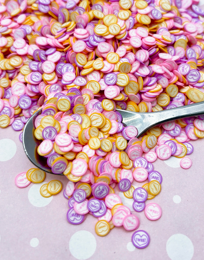 a pile of pink and yellow buttons next to a pair of scissors