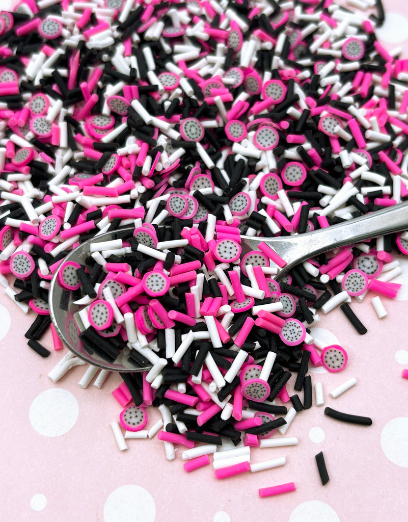 a pile of pink and black sprinkles and a spoon