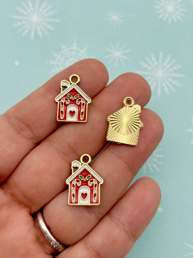 A hand holding three small, colorful charms in the shape of houses against a snowy background.