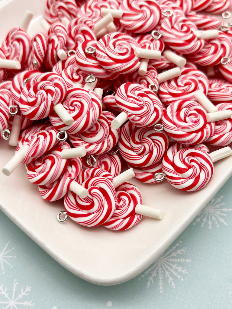 a white plate filled with numerous red and white striped lollipops, each with a white candy cane attached to it.