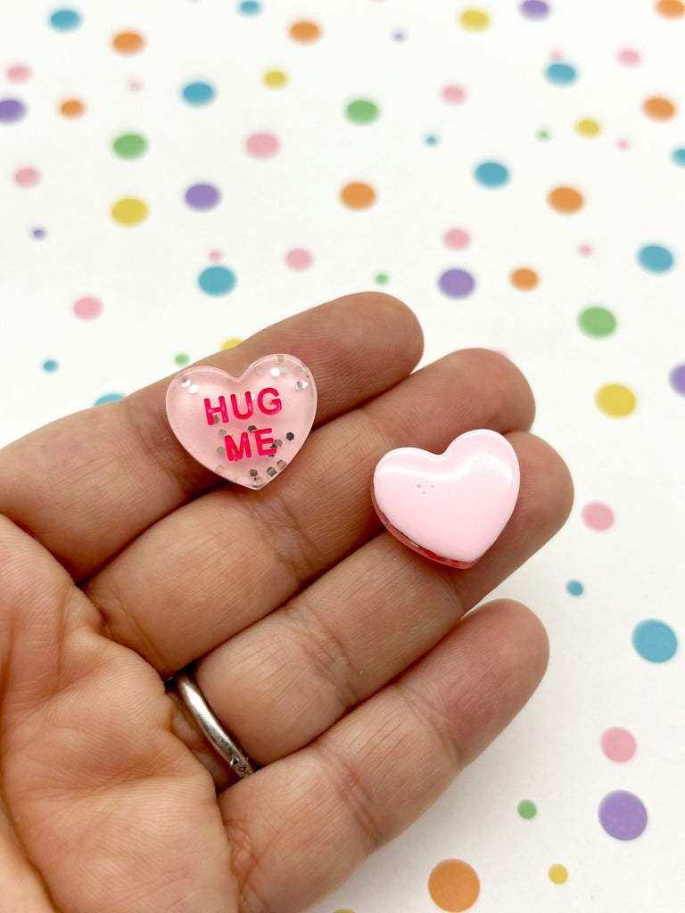 a person holding two small hearts in their hand