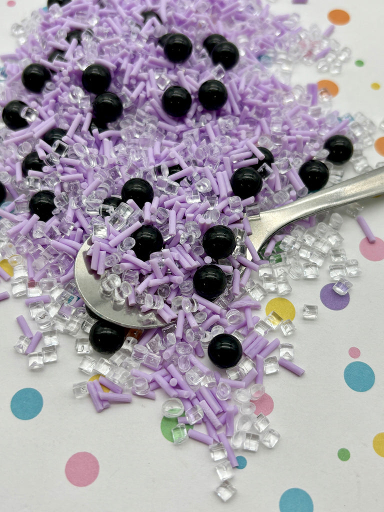 a spoon full of purple and black sprinkles