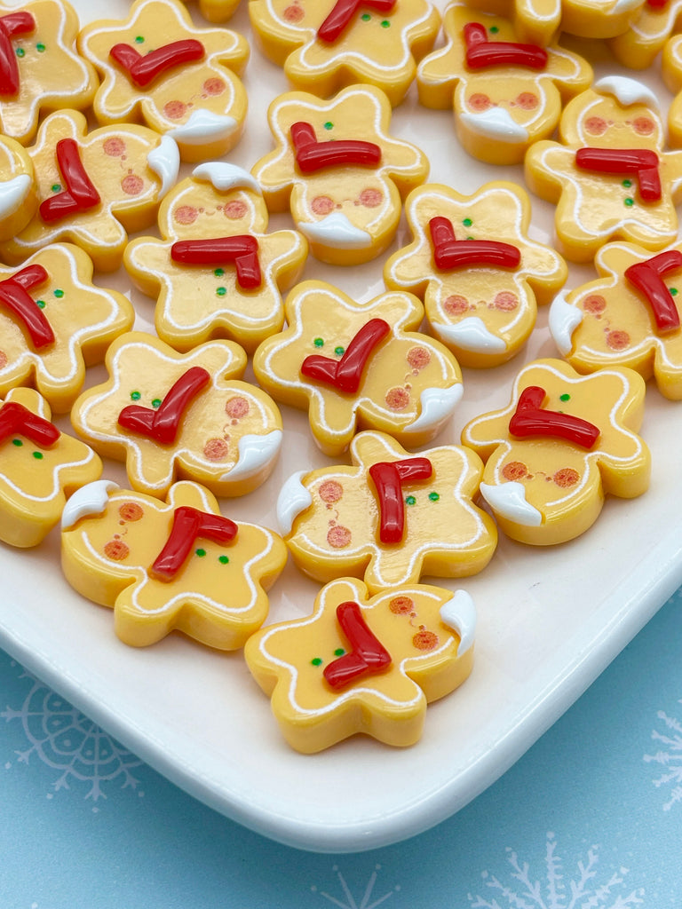 a white plate filled with yellow gingerbread cookies decorated with red and green icing, arranged in a visually appealing manner.