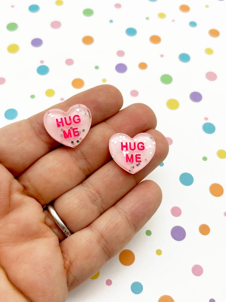 a person holding a pair of pink heart shaped earrings