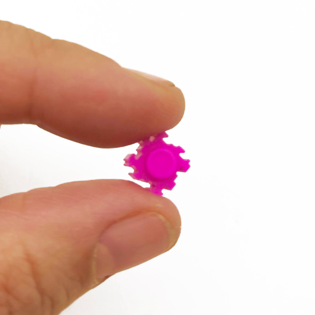 a person holding a tiny pink object in their hand