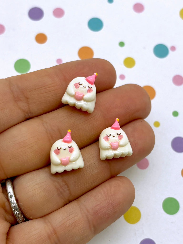 a hand holding a pair of tiny white unicorn earrings