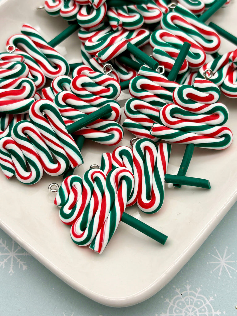 a white plate filled with colorful candy cane-shaped charms in red, green, and white stripes.